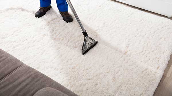 A white carpet being cleaned with a vacuum